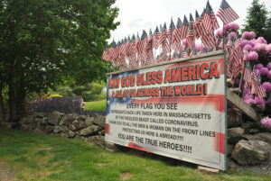 A sign explains the flag display on the property of Grafton’s Mike Labee. Labee has planted an American flag for every COVID-19 death in Massachusetts.