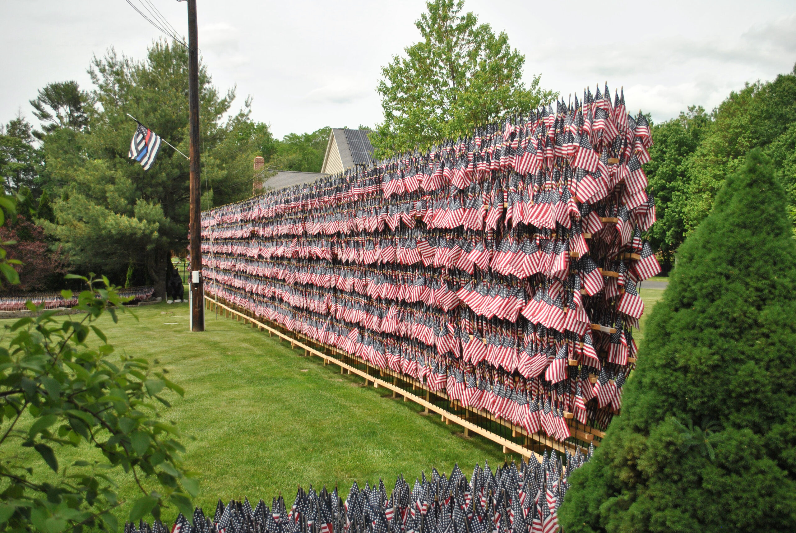 A large wall bears hundreds of flags memorializing the deaths of COVID-19 victims in Massachusetts.