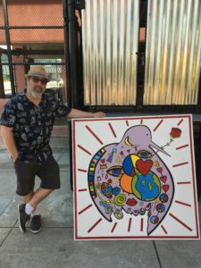 Stephen Beccia with his mural “Love Peace and Harmony” (acrylic on board, 48” x 48”) for Fitchburg’s Activate Mill Street Photo/submitted