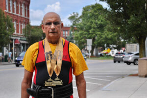 Harmesh Sharma stands near downtown Westborough wearing his powerlifting medals.
