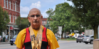 Harmesh Sharma stands near downtown Westborough wearing his powerlifting medals.