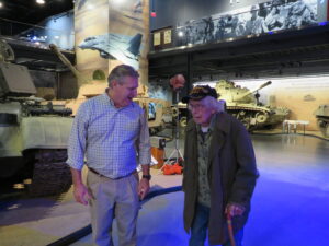 Hunter Cheney, left, director of marketing and communication for the American Heritage Museum in Hudson, escorts 101-year-old WWII veteran Russell Phipps.