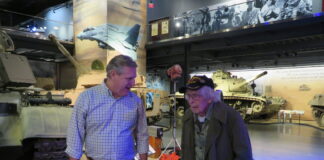 Hunter Cheney, left, director of marketing and communication for the American Heritage Museum in Hudson, escorts 101-year-old WWII veteran Russell Phipps.