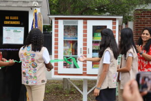 Three members of Girl Scout Troop 11087 cut the ribbon and officially open the Puzzle Hub. (Photo/Evan Walsh)