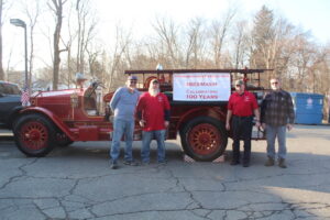 Northborough Firefighters Association members Paul Fiske, Shay Bailey, Peter Stone and David Hunt stand in front of the town’s 1923 Maxim fire engine. (Photo/Laura Hayes)