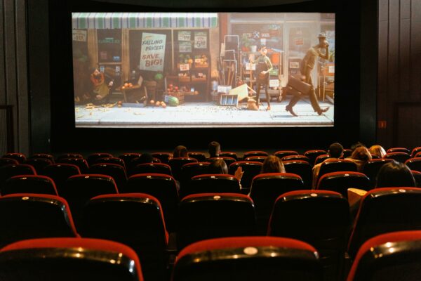 Movie theater screen displaying film, seniors enjoying affordable movie discounts in Westborough, MA.