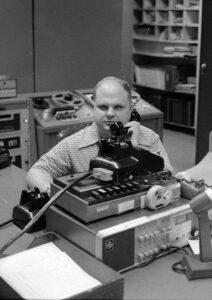 Ken Meyer, blind radio producer, working at a vintage radio broadcasting console in Boston.