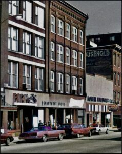 Birke’s Department Store in Lowell, featuring the storefront with bold signage, vintage cars parked outside, and surrounding historical buildings, reflecting the unique shopping experience and community impact described in the article.