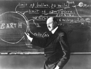 Robert H. Goddard presenting rocketry concepts at a chalkboard, illustrating limits of Earth's atmosphere and space, with "EARTH" prominently displayed.