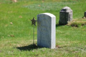 Marble headstone of Civil War veteran Josiah (Joseph) Warren Houghton, marked by a star-shaped military insignia, in a cemetery setting.