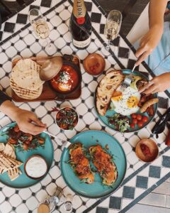 Gourmet dining experience featuring colorful plates of spring-inspired dishes, fresh ingredients, and sparkling beverages, set on a patterned table, ideal for a culinary retreat.