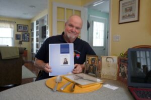 Eric Metcalf holding book about grandfather's POW story and World War II military service.