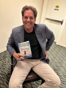 Glenn Cort holding "Letters to Mikey" book promoting hope and optimism for young Americans.