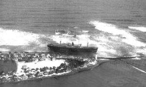 The grounded SS Etrusco cargo ship near Scituate Lighthouse and rocky shore.