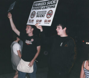 Chris Wrenn and vendor selling "Yankees Suck" merchandise near Fenway Park, promoting Bridge Nine Records.
