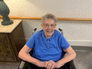 Kathleen Garvey, 100 years old, smiling in a wheelchair at St. Patrick’s Manor