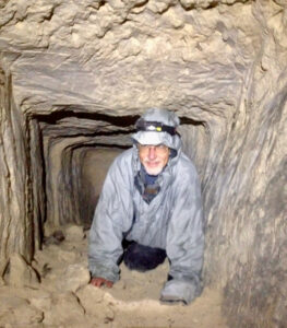 Evan Hadingham exploring a dark cave tunnel photographing ancient cave art