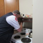 Lt. Chris Dano installs a firestop over a resident’s stove at the Colonial Gardens complex. 