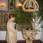 A woman on a Family Trees Tours trip looks at the Baptismal Font in the church that her ancestors attended.
